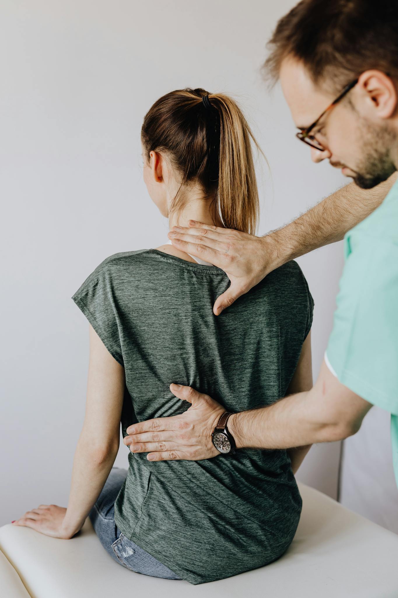 A chiropractor examines a patient's spine in a clinical setting. Health care and rehabilitation focus.