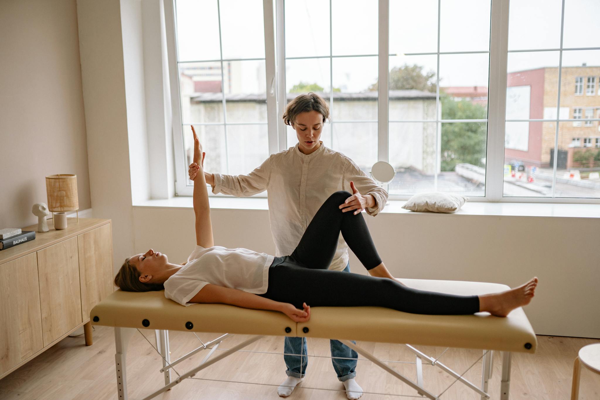 A specialist performs therapy on a woman lying on a massage table in a modern clinic setting.