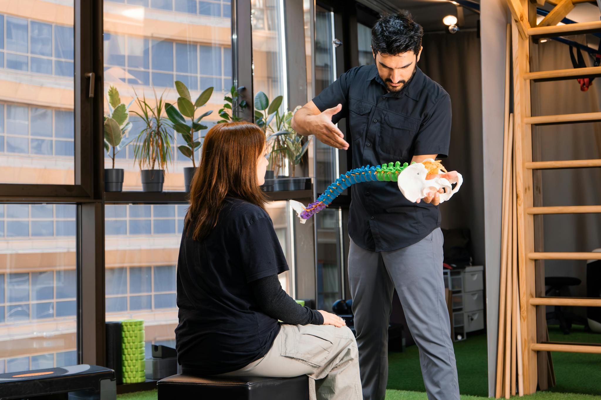 Chiropractor demonstrating spine anatomy to a patient during consultation indoors.